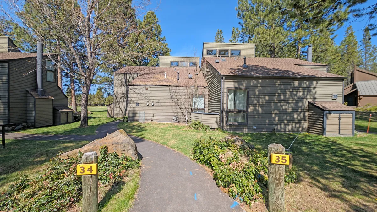 A welcoming exterior pathway bordered by green landscaping, with clearly visible numbered posts for homes 34 and 35. The peaceful surroundings and well-maintained grounds hint at the easy access to outdoor spaces and community amenities.
