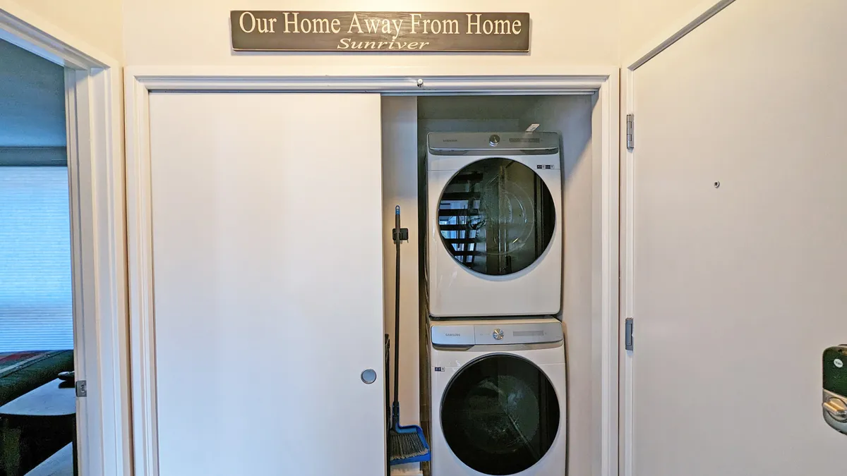This image shows a dedicated laundry area featuring a washer and dryer with a homey sign above the doorway. The space is organized and inviting, conveying a sense of convenience for guests who want to keep their outdoor gear fresh after long days of exploring.
